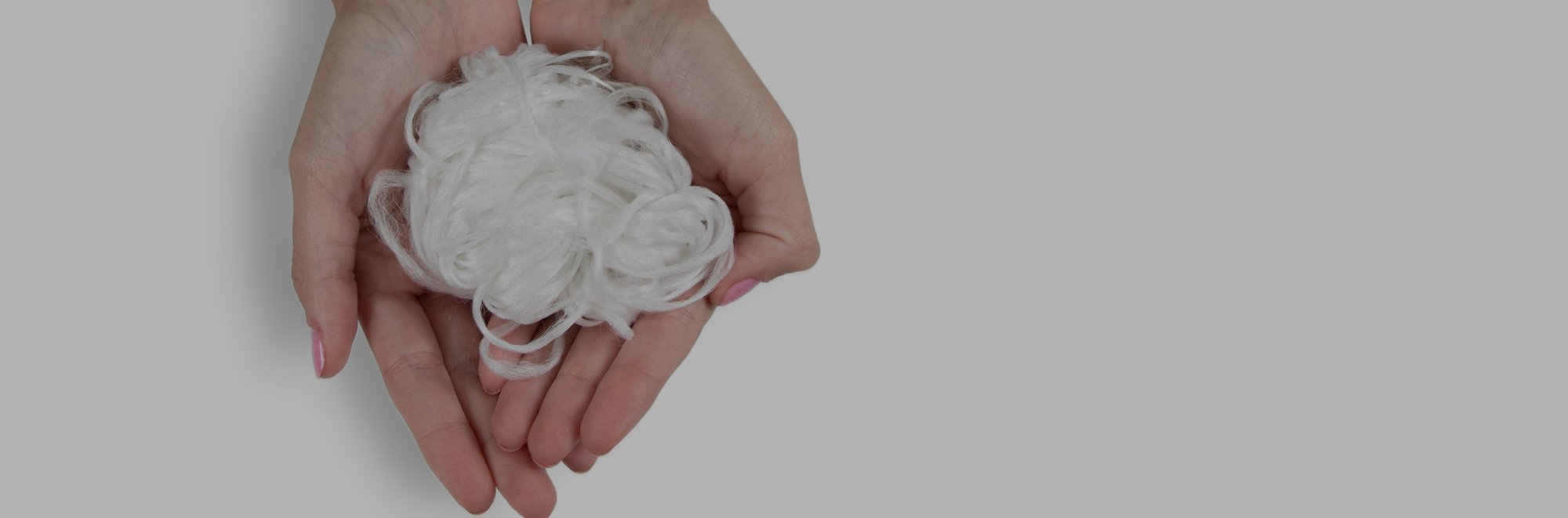 Hands holding PET carpet fiber on a white backdrop